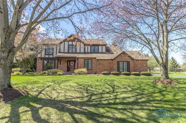 tudor house with brick siding and a front lawn