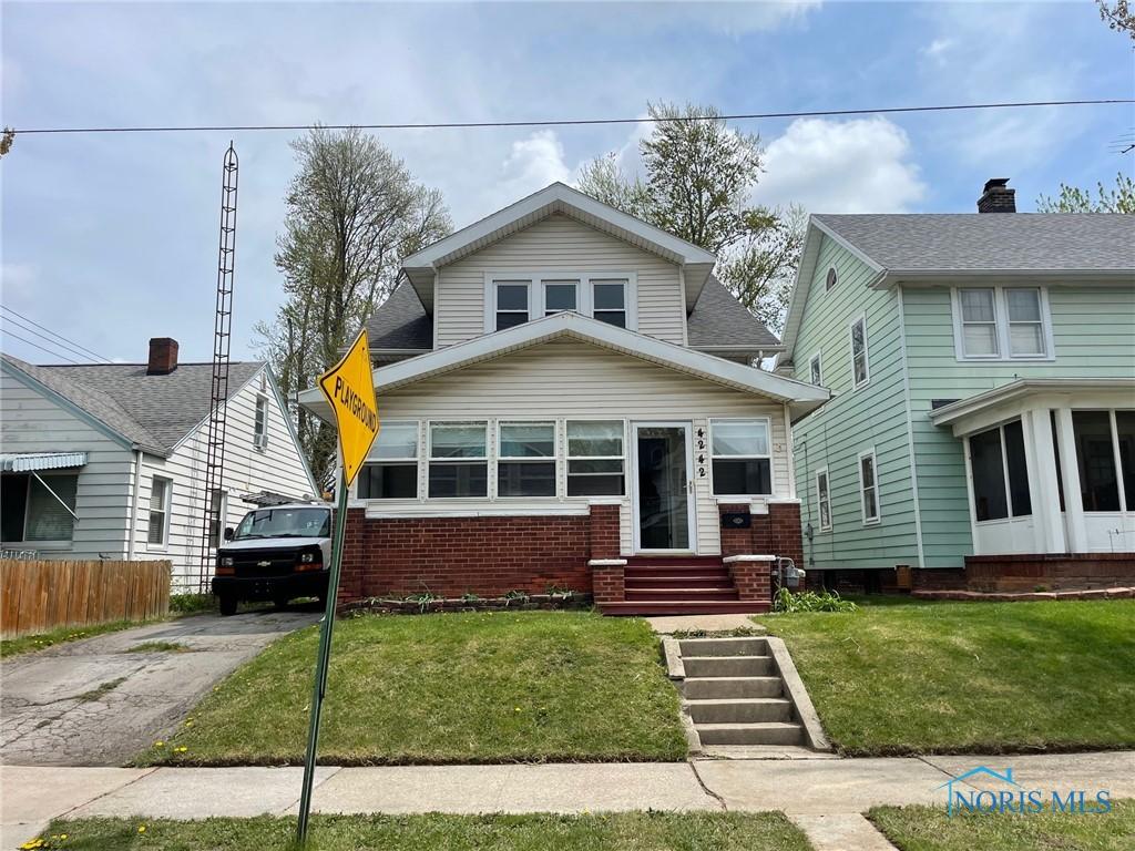 bungalow-style house with brick siding, concrete driveway, a front yard, and entry steps