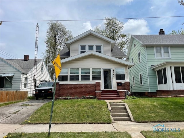 bungalow-style house with brick siding, concrete driveway, a front yard, and entry steps