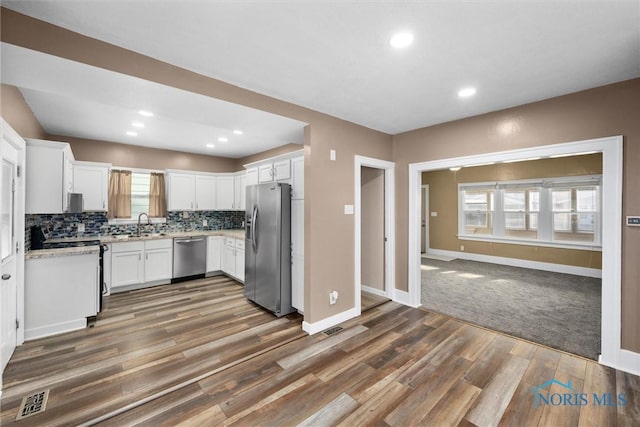 4242 Fairview Dr, Toledo, OH 43612 - kitchen featuring stainless steel appliances, wood finished floors, white cabinets, baseboards, and tasteful backsplash