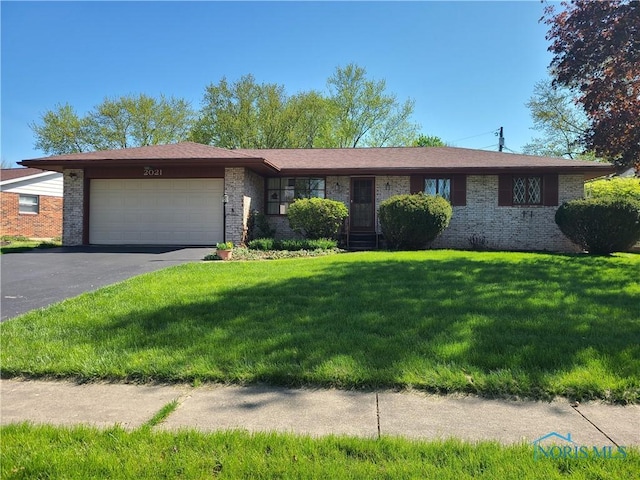 ranch-style house featuring an attached garage, aphalt driveway, a front lawn, and brick siding