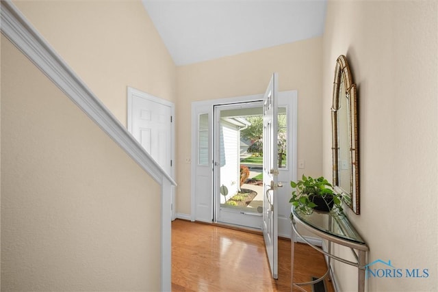 foyer featuring baseboards, light wood-style flooring, and lofted ceiling