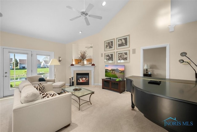 living area featuring high vaulted ceiling, a glass covered fireplace, light carpet, and ceiling fan