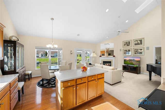 kitchen featuring a glass covered fireplace, a center island, light countertops, vaulted ceiling, and hanging light fixtures