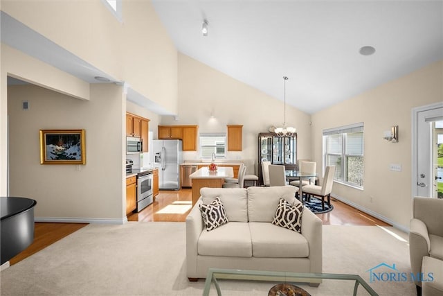 living room with visible vents, baseboards, high vaulted ceiling, light colored carpet, and a chandelier
