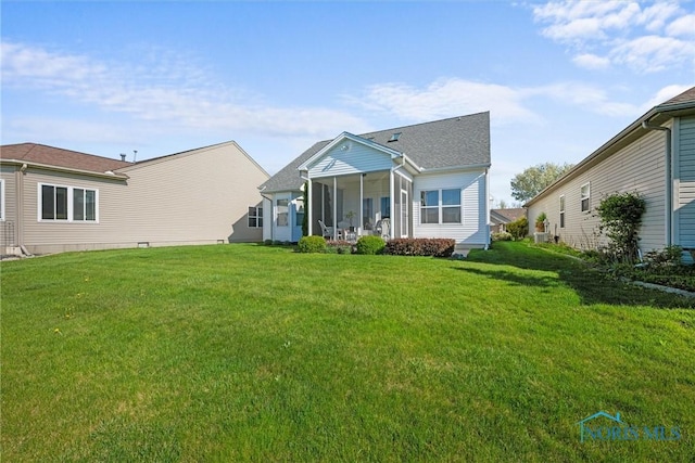 rear view of house featuring a lawn and a sunroom