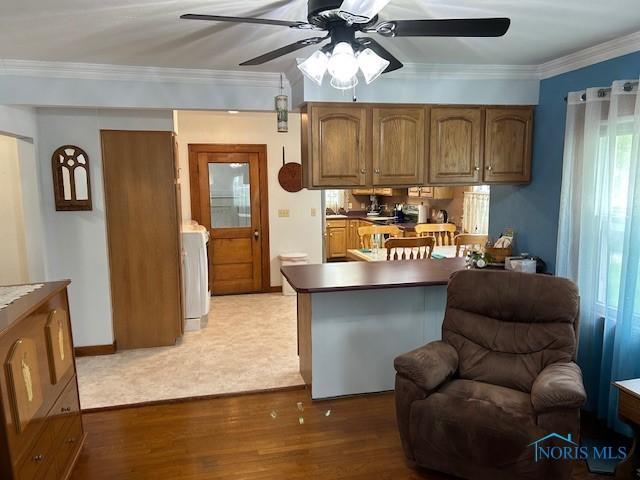 163 E Hull St, Edgerton, OH 43517 - kitchen featuring washer / dryer, brown cabinets, wood finished floors, crown molding, and a ceiling fan