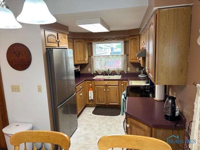163 E Hull St, Edgerton, OH 43517 - kitchen featuring a sink, brown cabinets, freestanding refrigerator, under cabinet range hood, and dark countertops