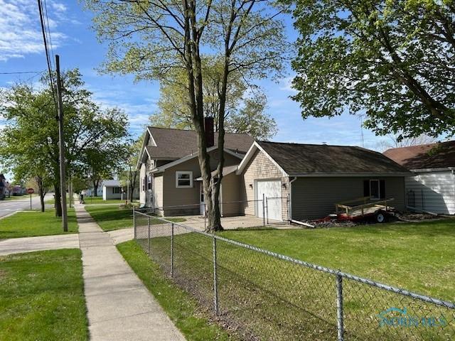 163 E Hull St, Edgerton, OH 43517 - view of front of property featuring fence private yard, an attached garage, and a front lawn