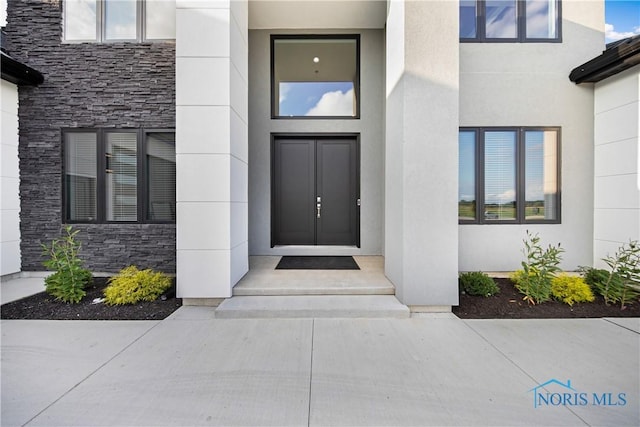 doorway to property with stucco siding and stone siding