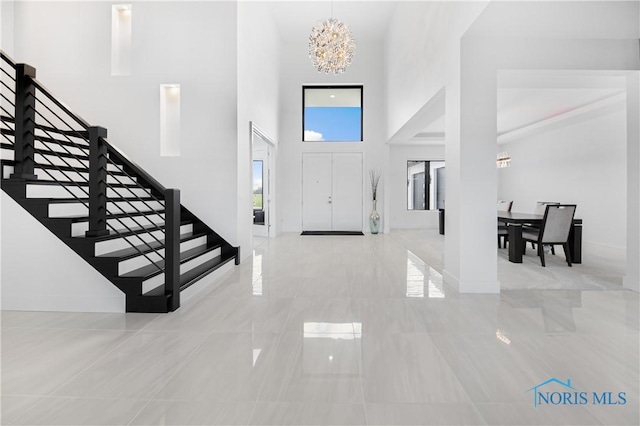 entrance foyer featuring an inviting chandelier, baseboards, stairs, and a towering ceiling