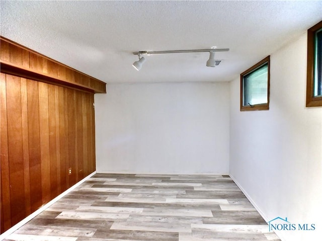 416 Donbar Dr, Bowling Green, OH 43402 - spare room featuring rail lighting, a textured ceiling, wood finished floors, and wooden walls