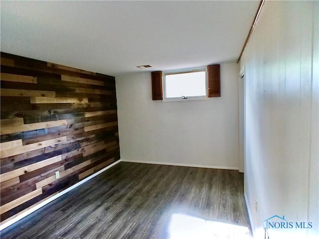 416 Donbar Dr, Bowling Green, OH 43402 - unfurnished room with dark wood-type flooring, baseboards, wooden walls, and visible vents
