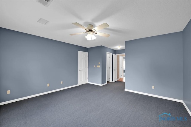 spare room with baseboards, a ceiling fan, dark carpet, and visible vents