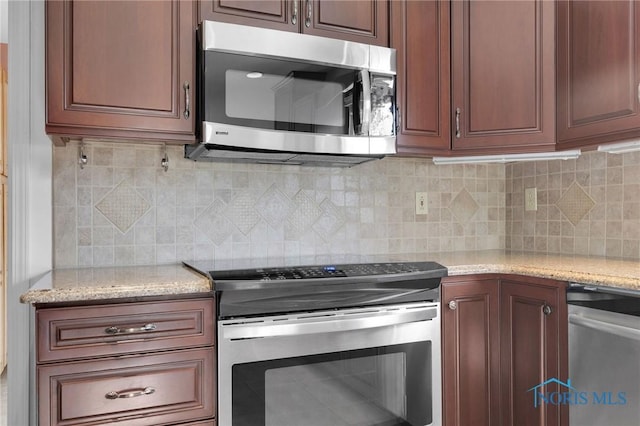 kitchen with light stone countertops, appliances with stainless steel finishes, and decorative backsplash