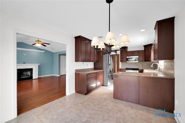 kitchen featuring stainless steel appliances, dark brown cabinetry, a sink, and ceiling fan with notable chandelier