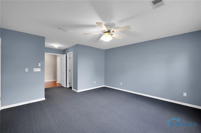 unfurnished room featuring visible vents, a ceiling fan, baseboards, and dark carpet