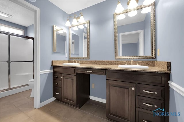 bathroom featuring tile patterned flooring, a sink, and a shower with shower door