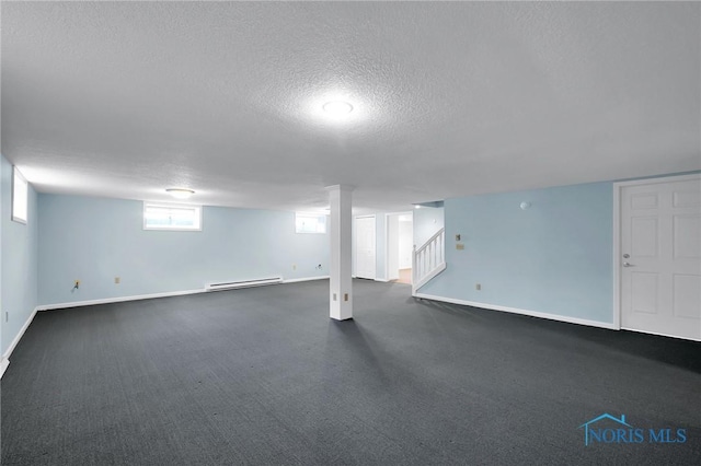 below grade area with baseboard heating, a textured ceiling, dark colored carpet, stairs, and baseboards