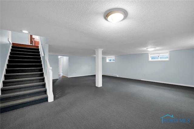 basement featuring dark carpet, baseboards, stairway, a textured ceiling, and a baseboard heating unit