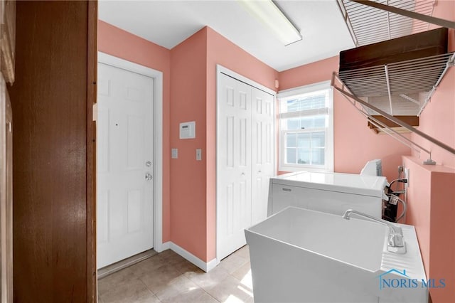 washroom with laundry area, light tile patterned floors, baseboards, a sink, and washer / dryer