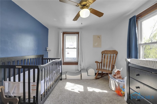 bedroom featuring a nursery area, multiple windows, and carpet