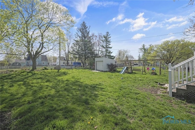 view of yard with a playground, fence, an outbuilding, and a storage shed