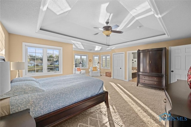 bedroom featuring carpet floors, baseboards, a tray ceiling, and connected bathroom