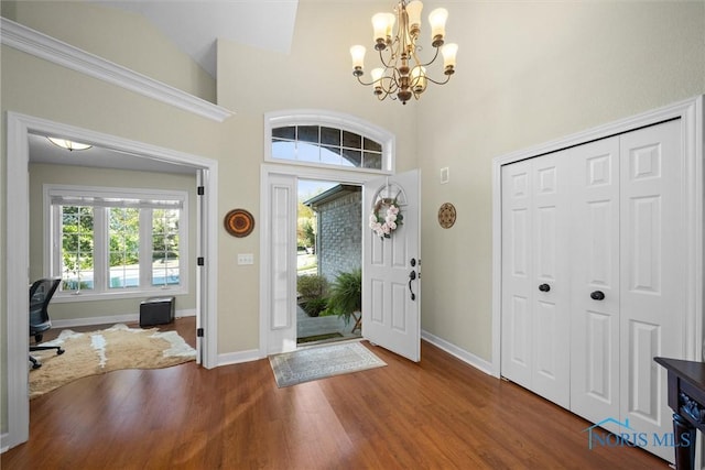 foyer featuring baseboards, an inviting chandelier, wood finished floors, and a towering ceiling