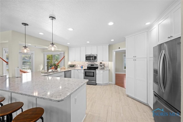 kitchen featuring white cabinetry, appliances with stainless steel finishes, a sink, and a kitchen bar