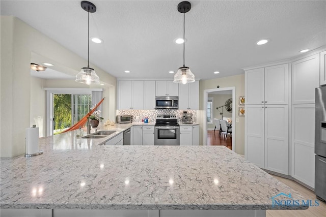 kitchen featuring light stone countertops, white cabinets, tasteful backsplash, a sink, and appliances with stainless steel finishes