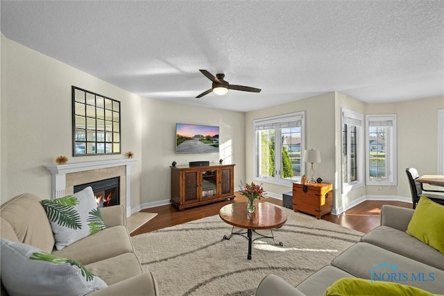 living area with baseboards, ceiling fan, and wood finished floors