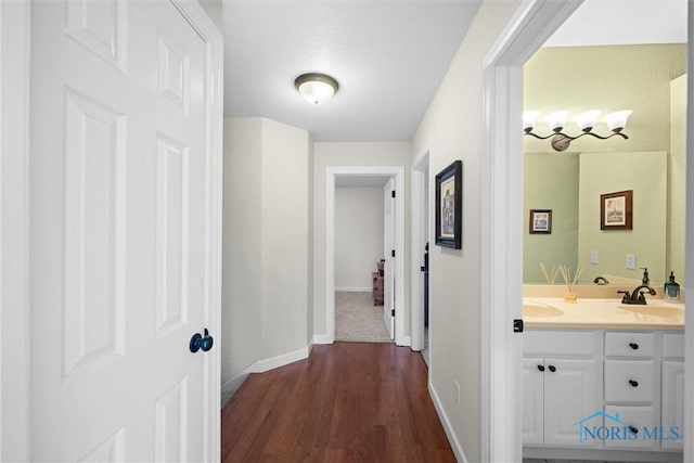 hall with baseboards, dark wood finished floors, and a sink