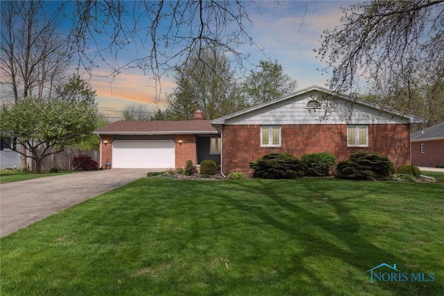 ranch-style house featuring a garage, driveway, a chimney, brick siding, and a yard