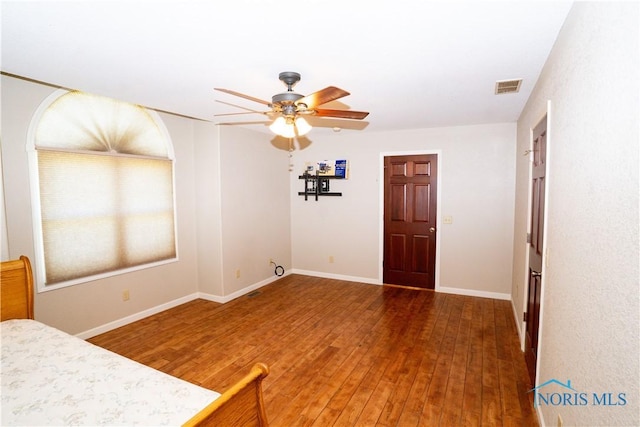 interior space with baseboards, ceiling fan, wood finished floors, and visible vents