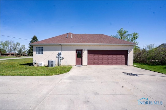 view of side of property featuring driveway, a lawn, a garage, central AC, and stucco siding