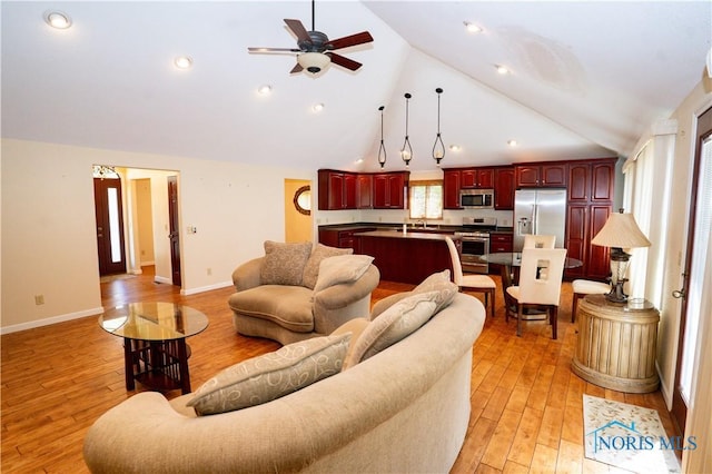 living area featuring a ceiling fan, baseboards, high vaulted ceiling, and light wood-type flooring