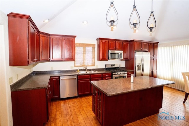 kitchen featuring a kitchen island, reddish brown cabinets, a sink, vaulted ceiling, and stainless steel appliances
