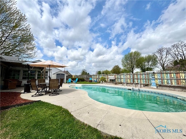 view of pool with a patio, a fenced backyard, a storage unit, a fenced in pool, and an outbuilding