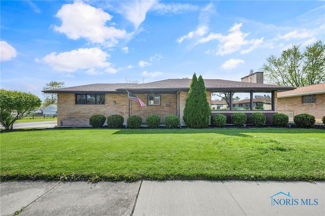 view of front of home featuring brick siding, a front lawn, and a chimney