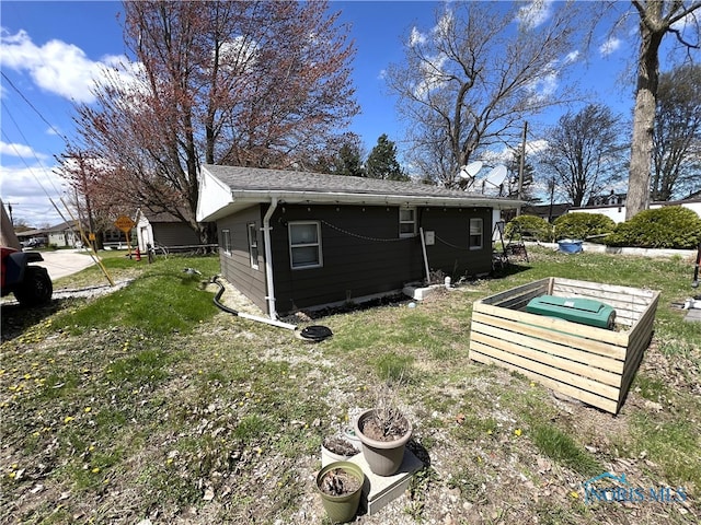 view of home's exterior with roof with shingles and a yard