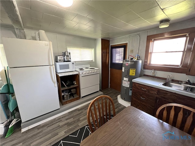 kitchen with white appliances, dark wood-style floors, light countertops, electric water heater, and a sink