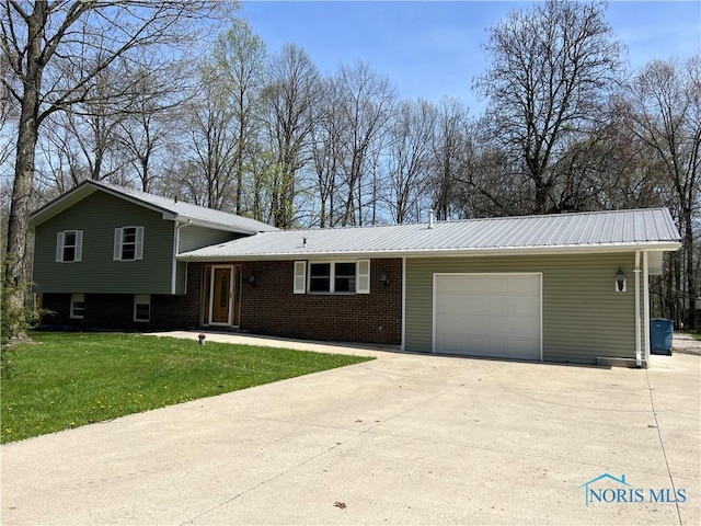split level home featuring driveway, metal roof, a front yard, brick siding, and an attached garage