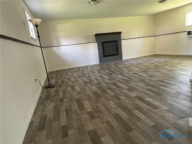 interior space featuring baseboards, a brick fireplace, and dark wood-style floors
