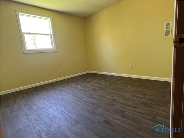 unfurnished room with baseboards, visible vents, and dark wood-style floors