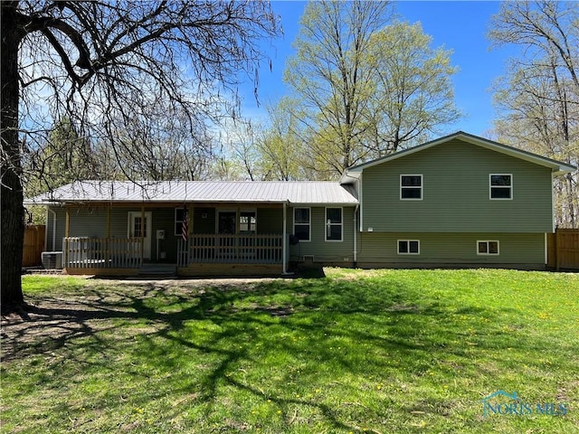 rear view of house featuring central air condition unit, fence, a yard, and metal roof