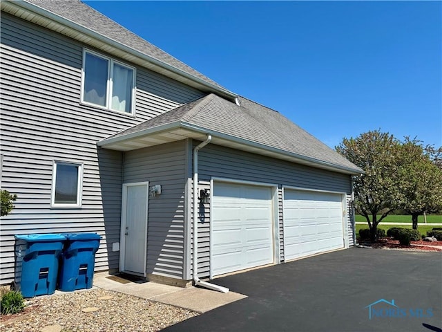 view of home's exterior featuring a shingled roof and driveway