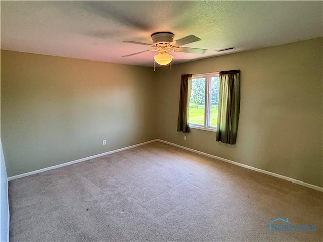carpeted empty room with a ceiling fan, baseboards, and visible vents