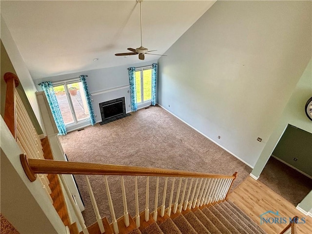 unfurnished living room with a healthy amount of sunlight, ceiling fan, carpet flooring, and a fireplace with flush hearth