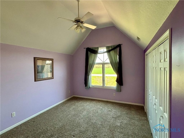 unfurnished bedroom with carpet, baseboards, vaulted ceiling, visible vents, and a closet